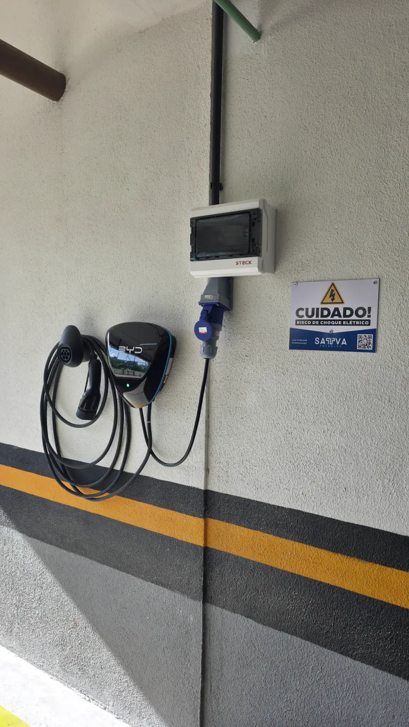 Carregador de carro elétrico instalado em parede de garagem, com cabo enrolado ao lado