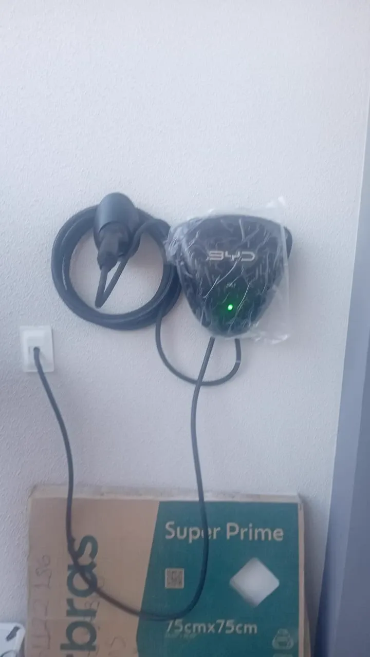 Carregador veicular ainda embalado, instalado ao lado de tomada de parede
